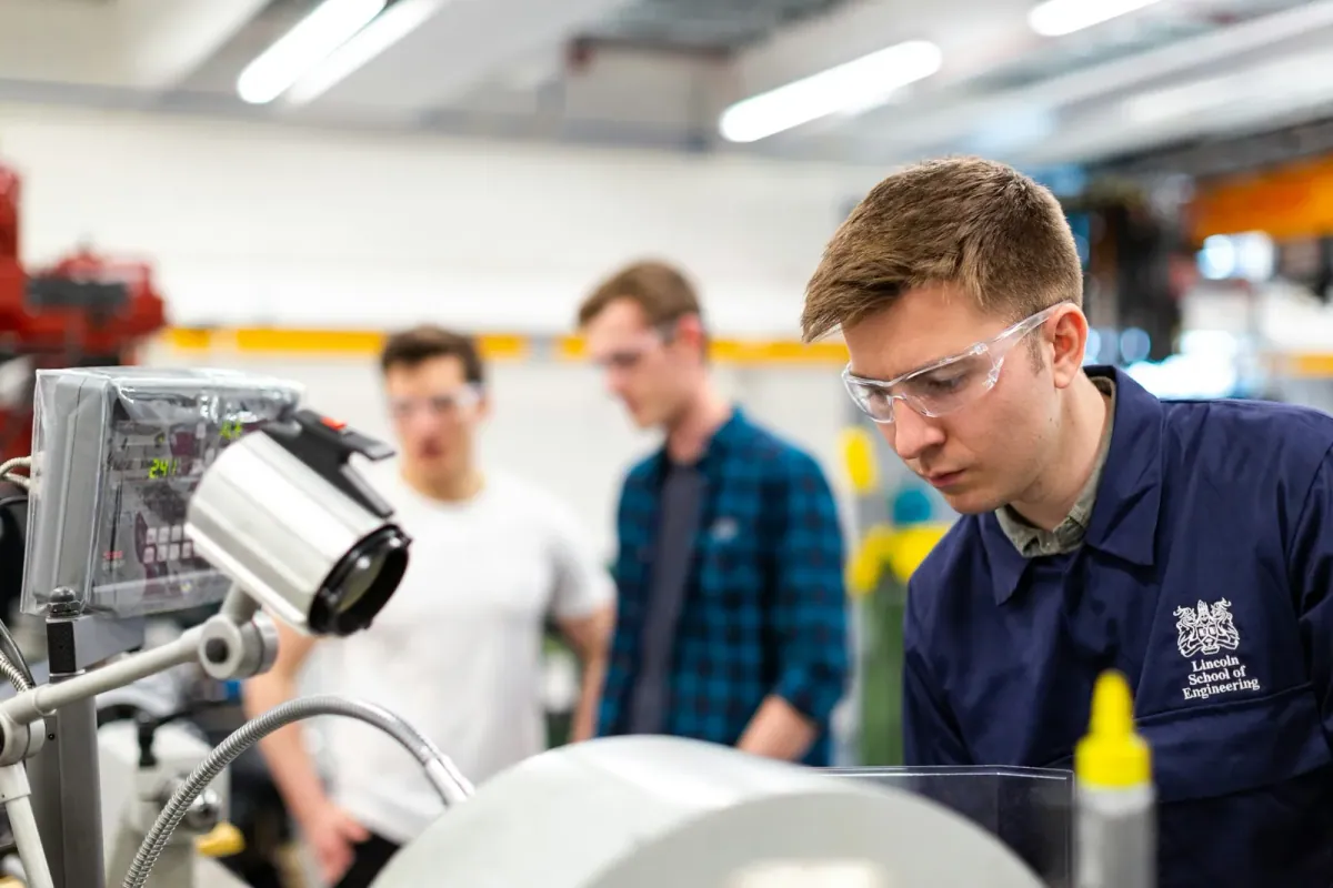 Técnicos con lentes de seguridad operando maquinaria en un taller de ingeniería